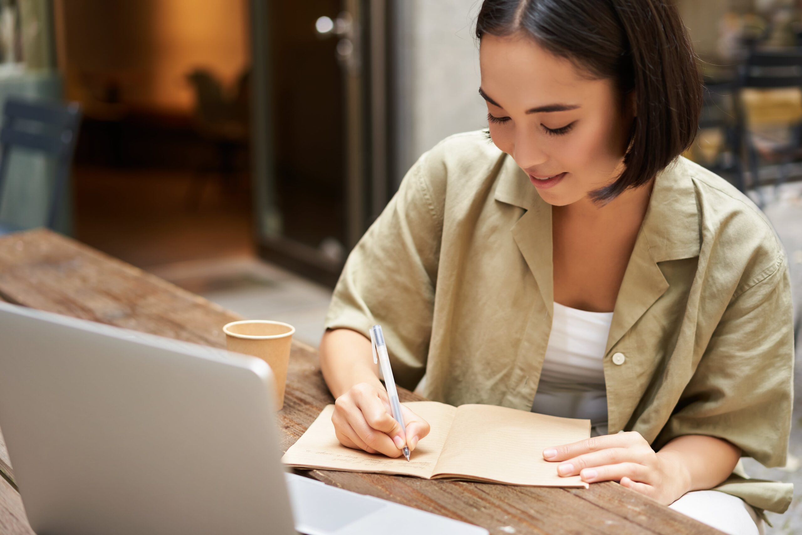 portrait-young-asian-woman-working-laptop-making-notes-writing-down-while-attending-online-lesson-work-meeting-min